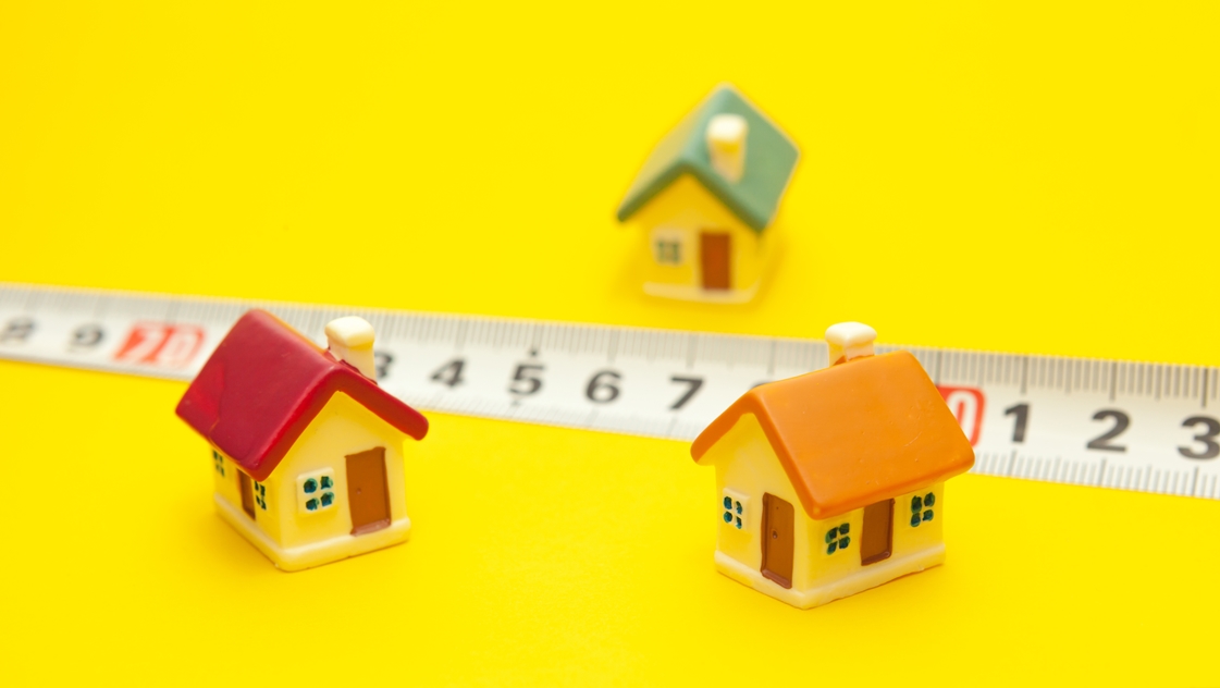 Colored houses on a yellow background with a measuring tape