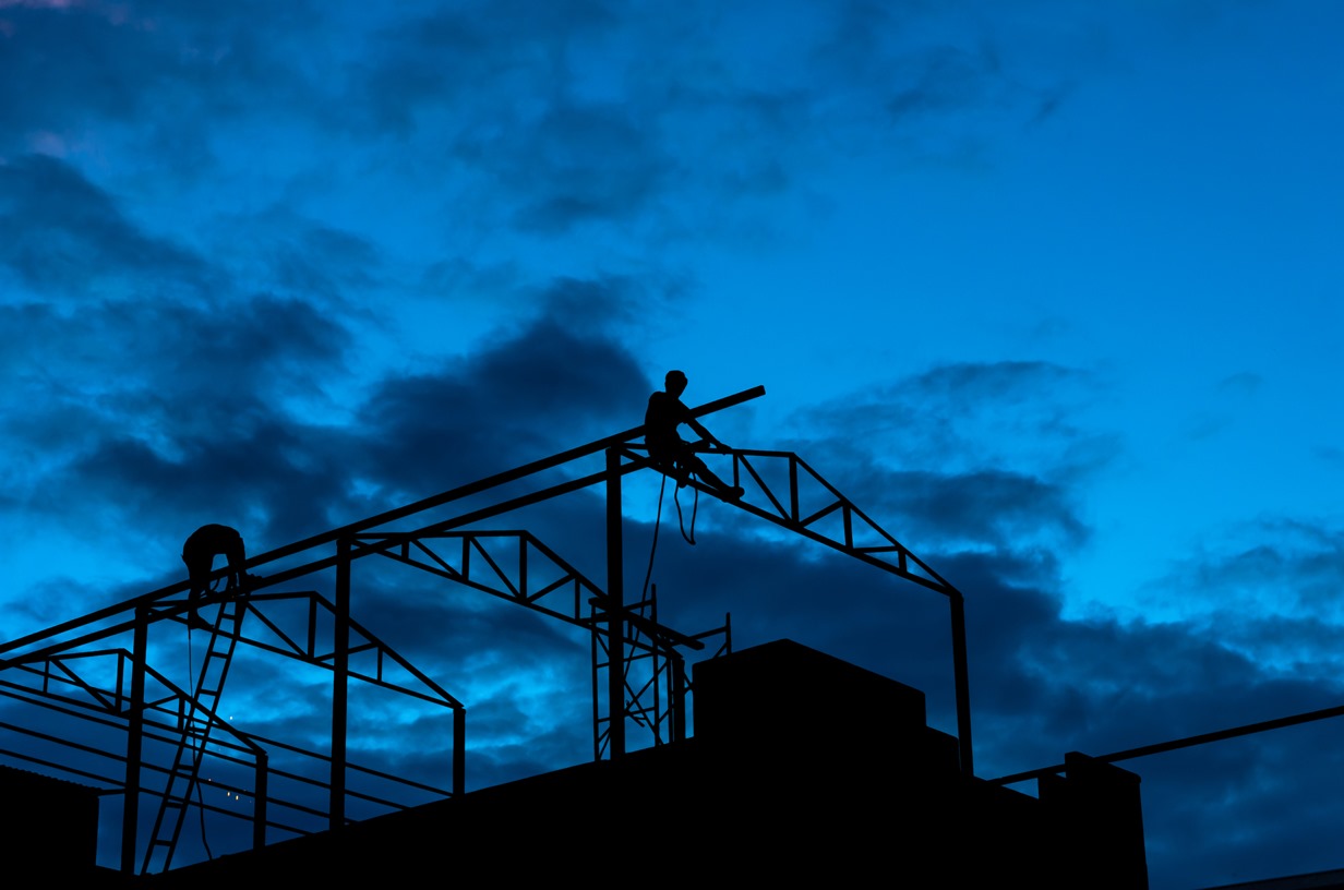 Silhouette of Carpenter working on top of the roof structure